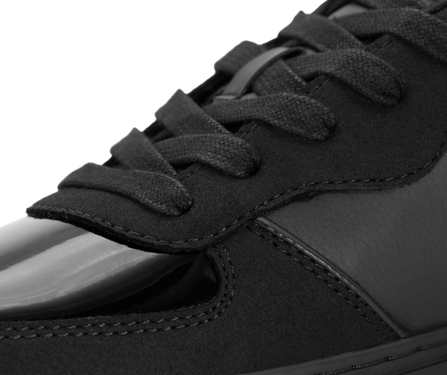 Nahaufnahme der Fuego Low-Top Dance Sneakers x Derek Hough mit schwarzen Schnürsenkeln, Wildleder und glänzenden Lederdetails.